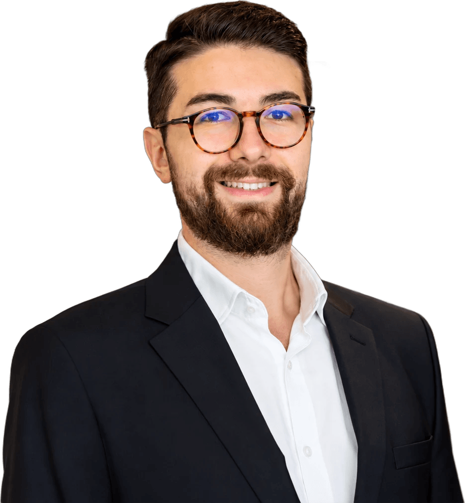 Erem Cem, smiling, in round tortoiseshell glasses, a dark blazer and a white shirt
